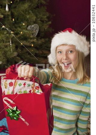 Teenage girl (13-15) wearing Santa hat holding Christmas gift Teenage girl (13-15) wearing Santa hat holding Christmas gift 10632441