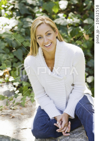 Portrait of smiling woman sitting in garden 10632558