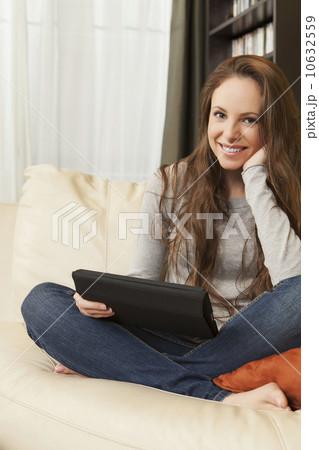 Smiling woman sitting on sofa with digital tablet 10632559