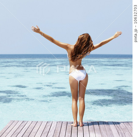 Young woman in bikini standing on jetty 10632703