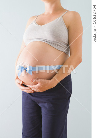 Pregnant woman’s belly wrapped in blue ribbon 10632704