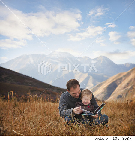 Father and son reading outdoors Father and son reading outdoors 10648037