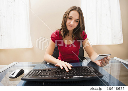 Young woman using computer and holding credit card Young woman using computer and holding credit card 10648625