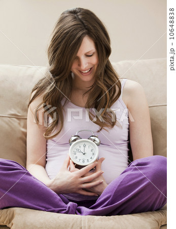 USA, Utah, Lehi, Young pregnant woman holding alarm clock 10648838