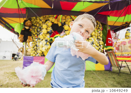 Boy (4-5) eating cotton candy in amusement park  10649249