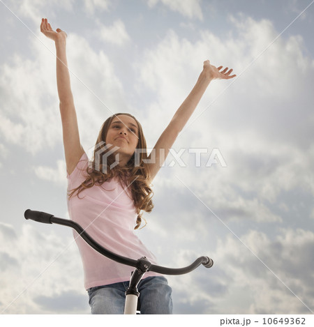 Pretty teenage girl with her arms raised while sitting on bike Pretty teenage girl with her arms raised while sitting on bike 10649362