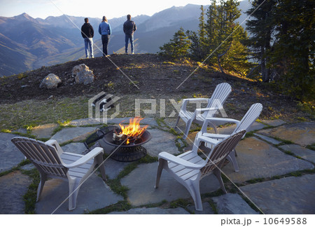 Three people standing near fire pit looking at landscape  10649588