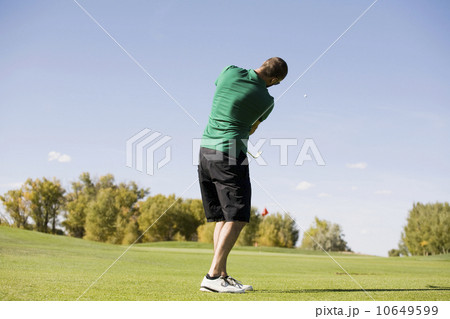 Rear view of man hitting ball on golf course Rear view of man hitting ball on golf course 10649599