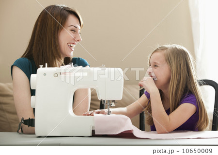 USA, Utah, Lehi, Girl (8-9) and young woman using sewing machine 10650009