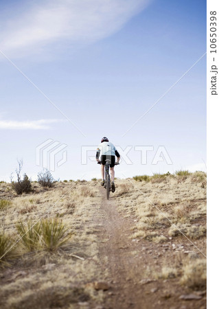 Rear view of man biking on trial 10650398