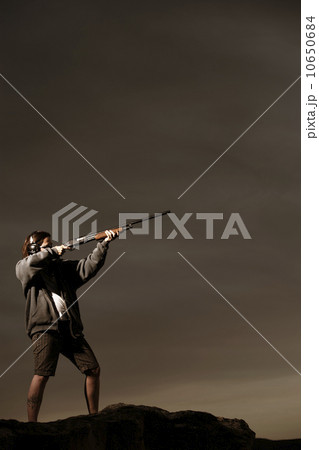 Man aiming rifle on rocks 10650684