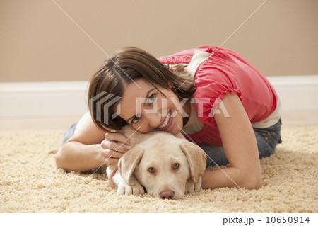 Portrait of woman embracing Labrador on carpet Portrait of woman embracing Labrador on carpet 10650914