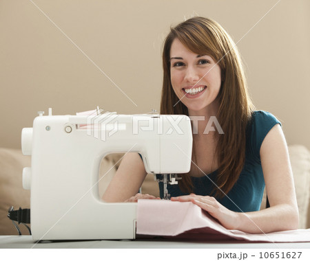 USA, Utah, Lehi, Portrait of smiling young woman using sewing machine USA, Utah, Lehi, Portrait of smiling young woman using sewing machine 10651627