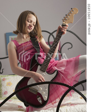 Young girls playing guitar on her bed Young girls playing guitar on her bed 10651850