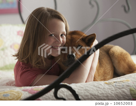 Young girl hugging dog on bed Young girl hugging dog on bed 10652003