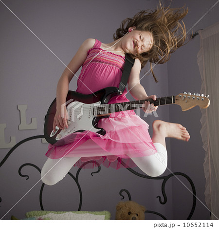 Young girls playing guitar on her bed Young girls playing guitar on her bed 10652114