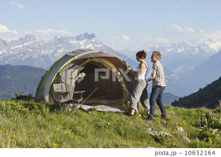 Switzerland, Leysin, Hikers pitching tent on meadow 10652164