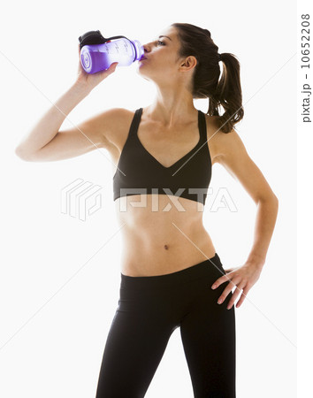 Young woman drinking water after exercising, studio shot Young woman drinking water after exercising, studio shot 10652208