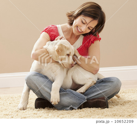 Woman embracing Labrador on carpet Woman embracing Labrador on carpet 10652209