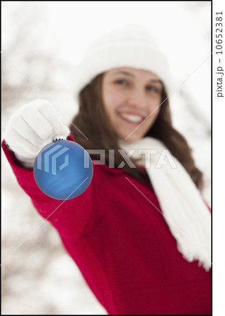 USA, Utah, Lehi, Portrait of young woman holding Christmas bauble outdoors USA, Utah, Lehi, Portrait of young woman holding Christmas bauble outdoors 10652381