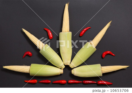 Fresh raw baby corn cobs with red non-stem chili peppers 10653706
