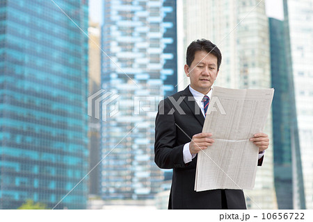 Successful entrepreneur stock agent business man reading newspaper in front of glass office building 10656722