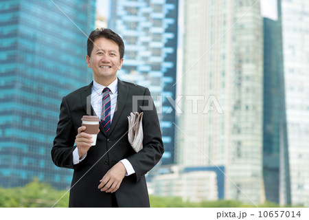 Successful entrepreneur business man holding coffee cup and newspaper in front of office building 10657014