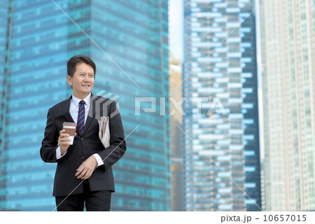 Successful entrepreneur business man holding coffee cup and newspaper in front of office building 10657015