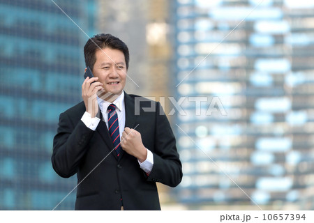 Successful entrepreneur business man hearing good news in front of glass office building 10657394