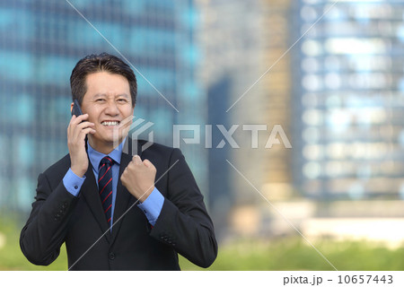 Successful entrepreneur business man hearing good news in front of glass office building 10657443