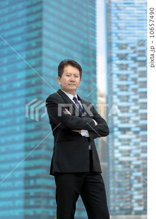 Successful entrepreneur business man standing in front of glass office building folding arms Successful entrepreneur business man standing in front of glass office building folding arms 10657490