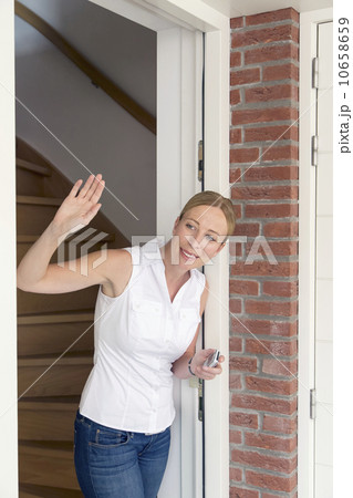 Woman opening door and waving Woman opening door and waving 10658659