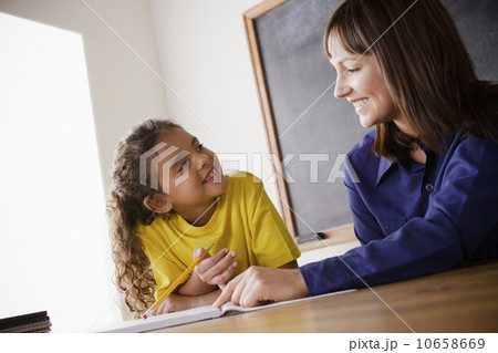 Schoolgirl writing with teacher in classroom Schoolgirl writing with teacher in classroom 10658669
