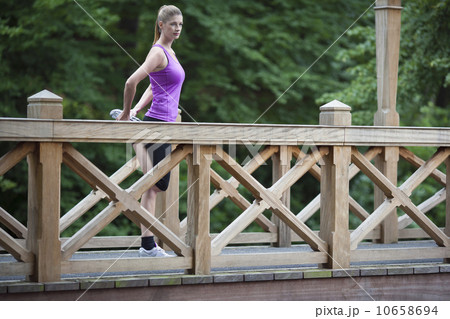 Young woman stretching leg on wooden bridge after running. Young woman stretching leg on wooden bridge after running. 10658694