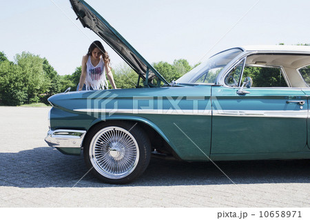 Woman standing near broken vintage car 10658971