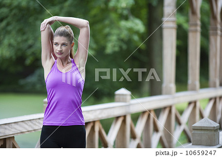 Young woman stretching arm on wooden bridge after running. 10659247