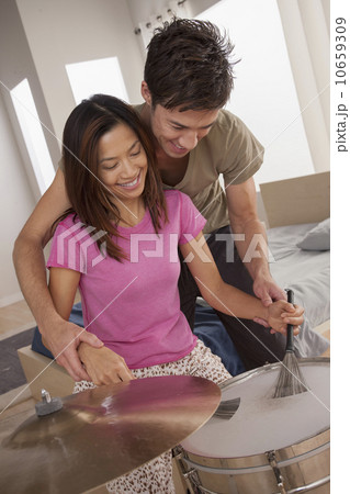 Man teaching woman how to play drums 10659309
