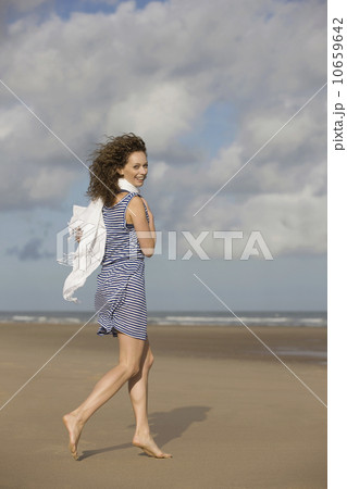 France, Pas-de-Calais, Escalles, Young woman strolling on empty beach 10659642