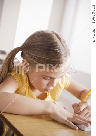 Schoolgirl focused on writing in classroom Schoolgirl focused on writing in classroom 10660613
