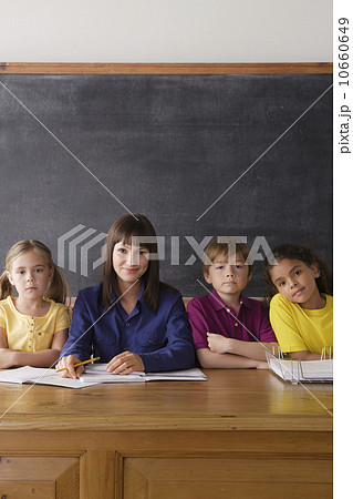 Teacher sitting by desk with group of pupils 10660649
