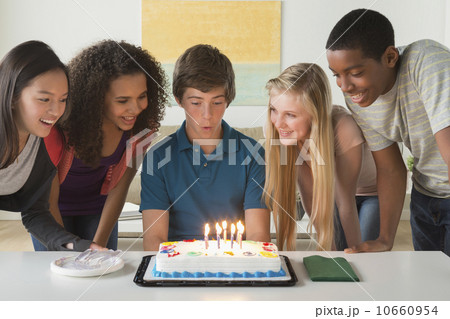 Children (12-13,14-15,16-17) blowing candles on birthday cake 10660954