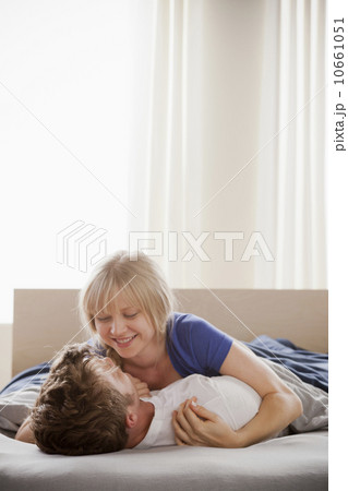 Woman lying atop man in bed Woman lying atop man in bed 10661051
