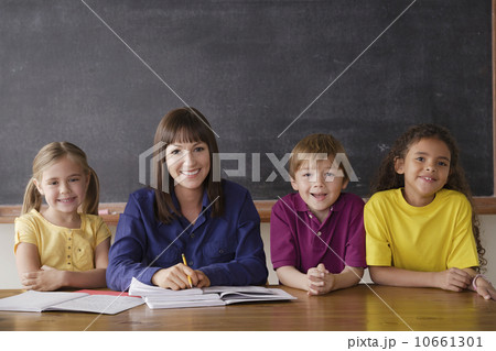 Teacher sitting by desk with group of pupils Teacher sitting by desk with group of pupils 10661301