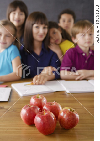 Teacher with group of pupils and apples on desk Teacher with group of pupils and apples on desk 10661303