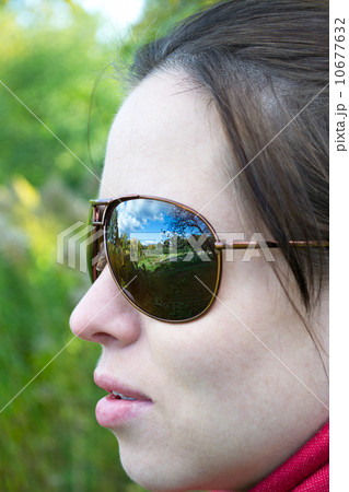 Dark glasses reflect the nature,worn by a young woman 10677632