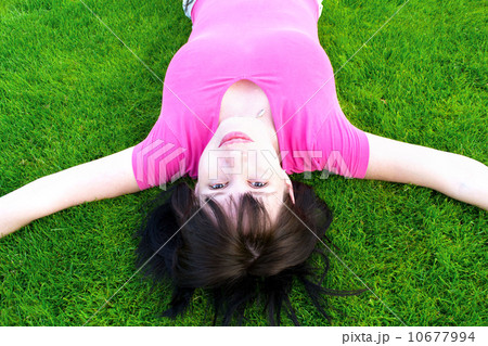 Young happy the woman lies on a green grass Young happy the woman lies on a green grass 10677994