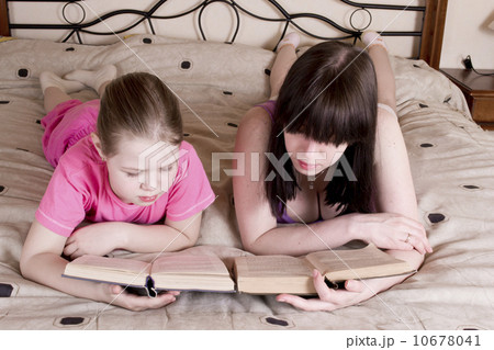 Girls reading book on bed Girls reading book on bed 10678041