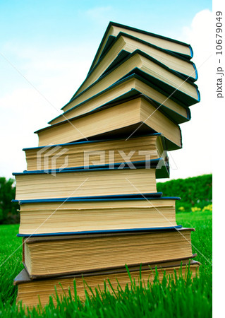 A stack of books lying on green grass A stack of books lying on green grass 10679049