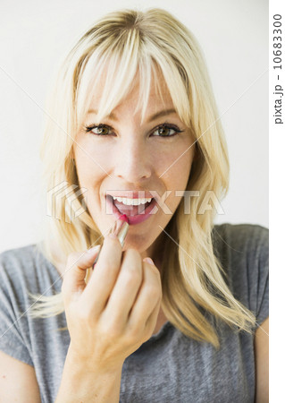 Woman applying lipstick, studio shot 10683300