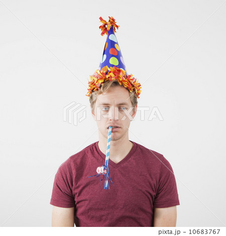 Displeased man with party hat and party horn blower 10683767